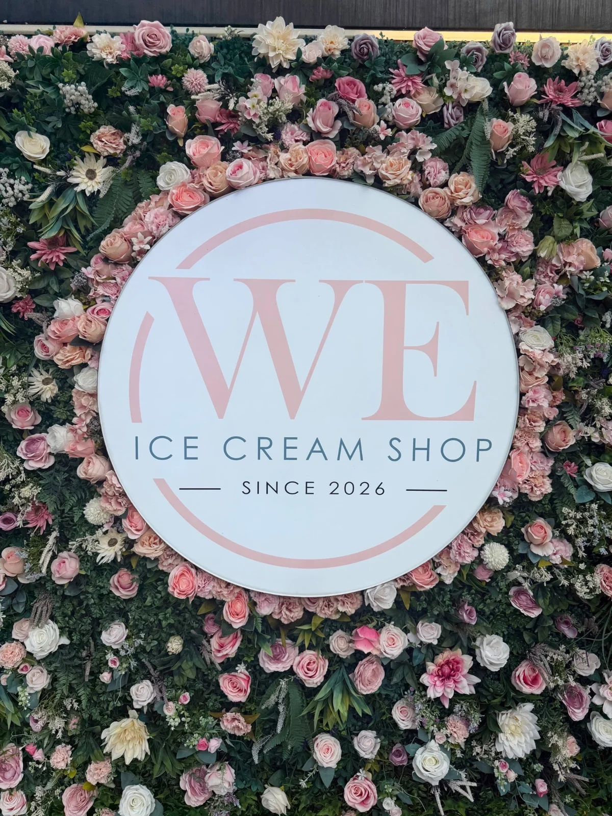 Logo de WE Ice Cream Shop rodeado de flores rosadas